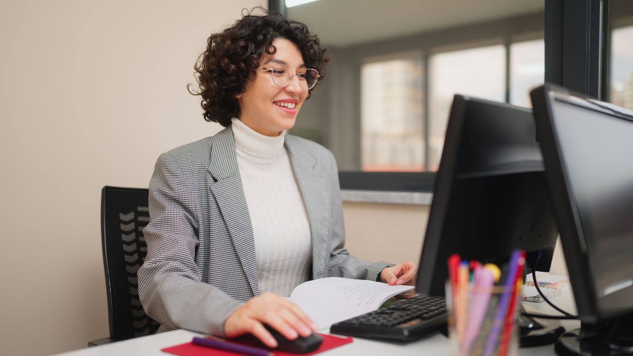 a teacher sitting at her desk working on her computer
