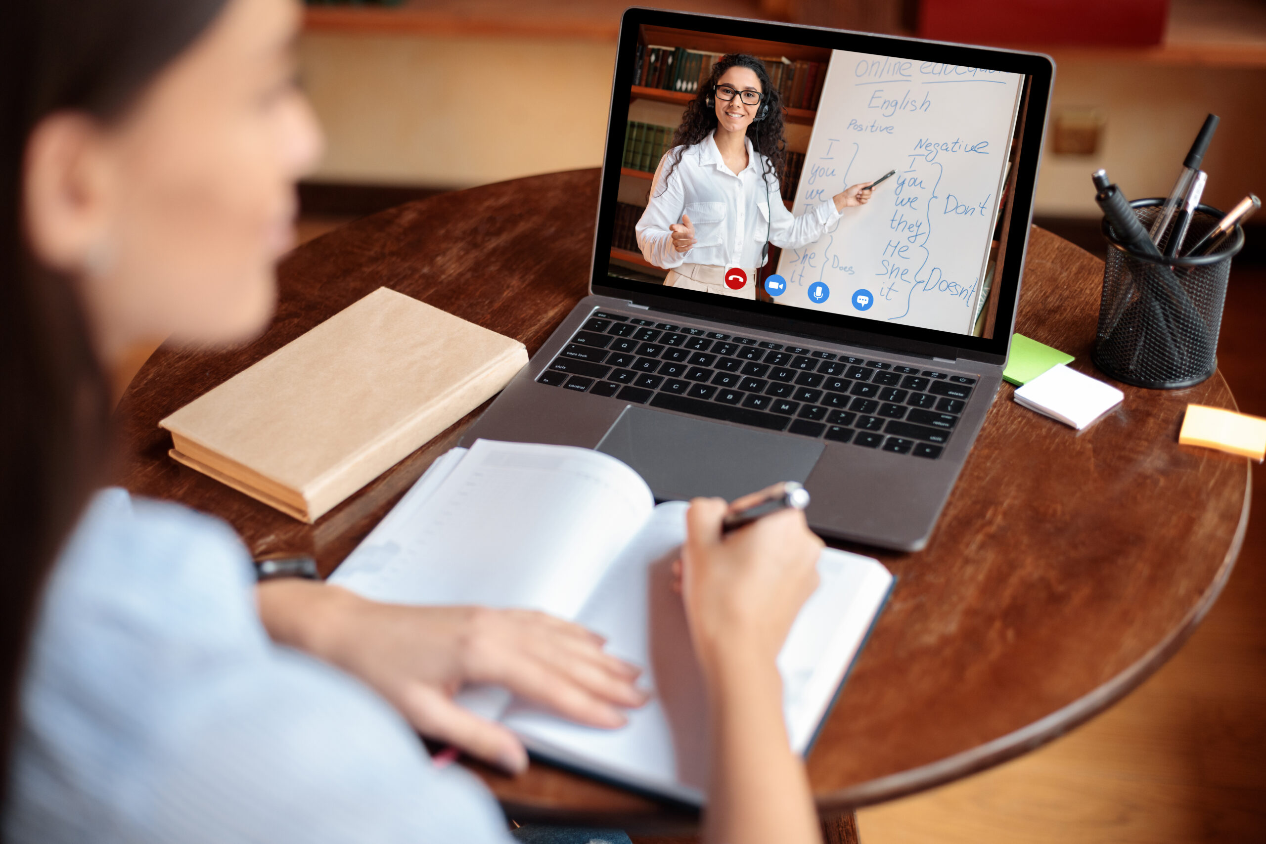 Student using laptop having online class with teacher, over shoulder Student using laptop having online class with teacher, over shoulder