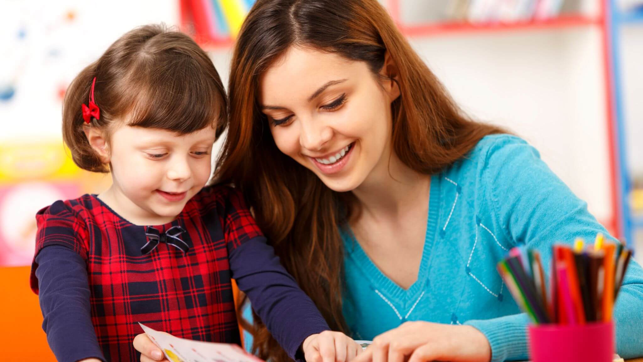 an au pair sitting with a young child reading a book