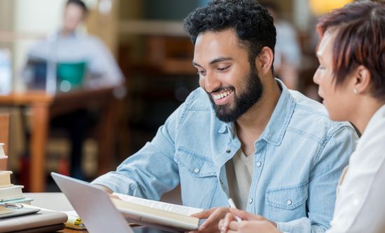 two students looking through a book passage at a desk.