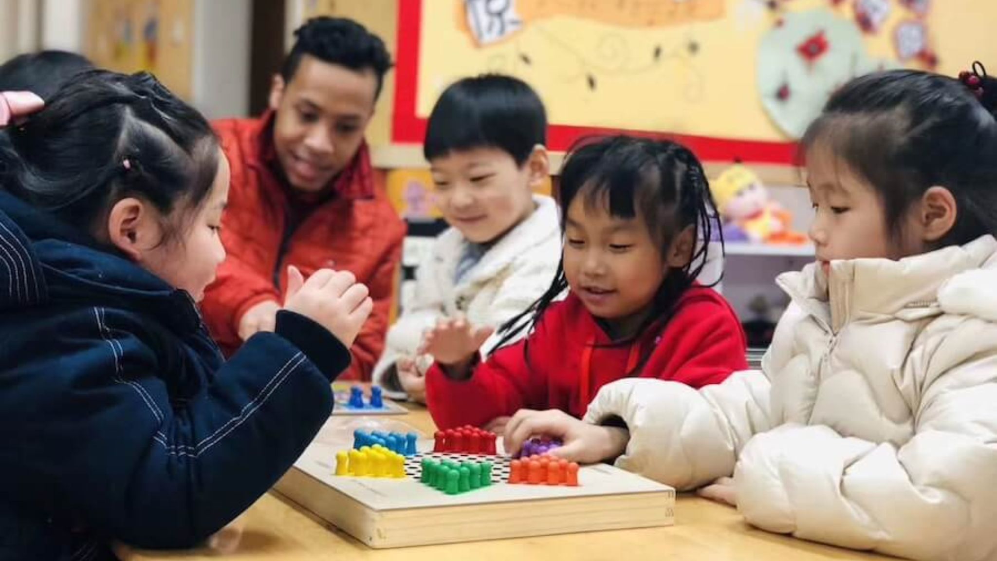 a teacher working with young students at a desk.