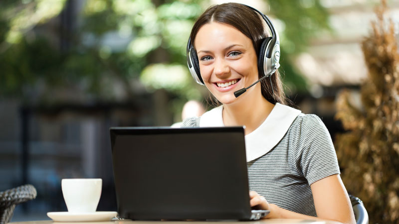Use your BridgeTEFL certification to teach English online! A young woman with headset on her laptop.