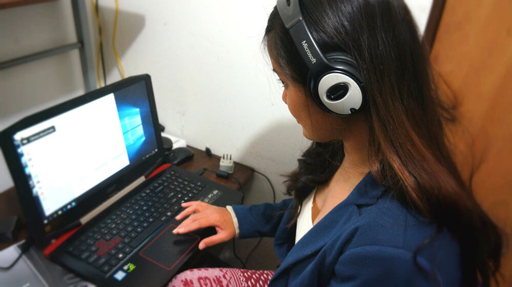 Bridge TEFL grad and author of this blog post, Krzl, wearing a headset while she prepares to teach English online from home.