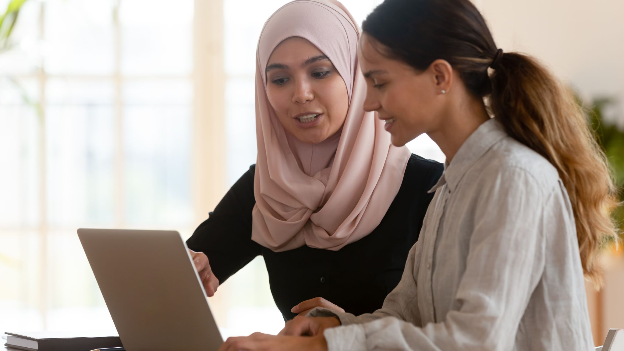 a teacher with a young adult student looking at a laptop