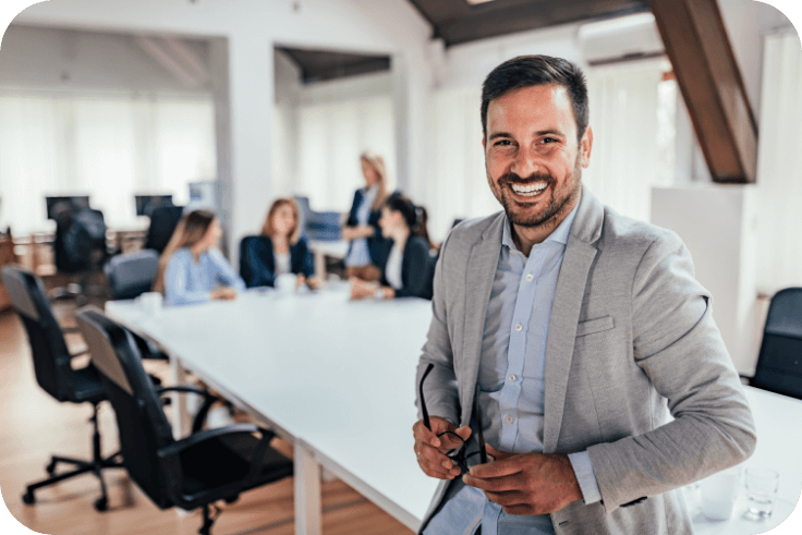 A smiling businessman in front of a table with colleagues having a meeting