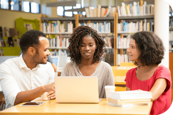 Three people talking at a table in front of a computer  